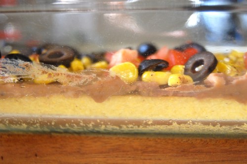 Mexican casserole side view of cornbread, beans, tomatoes and olives